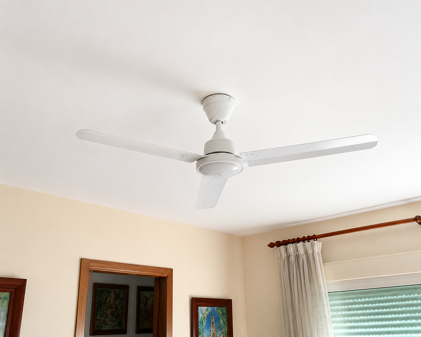 Ventilador de techo blanco de tres aspas instalado en el salón de una vivienda