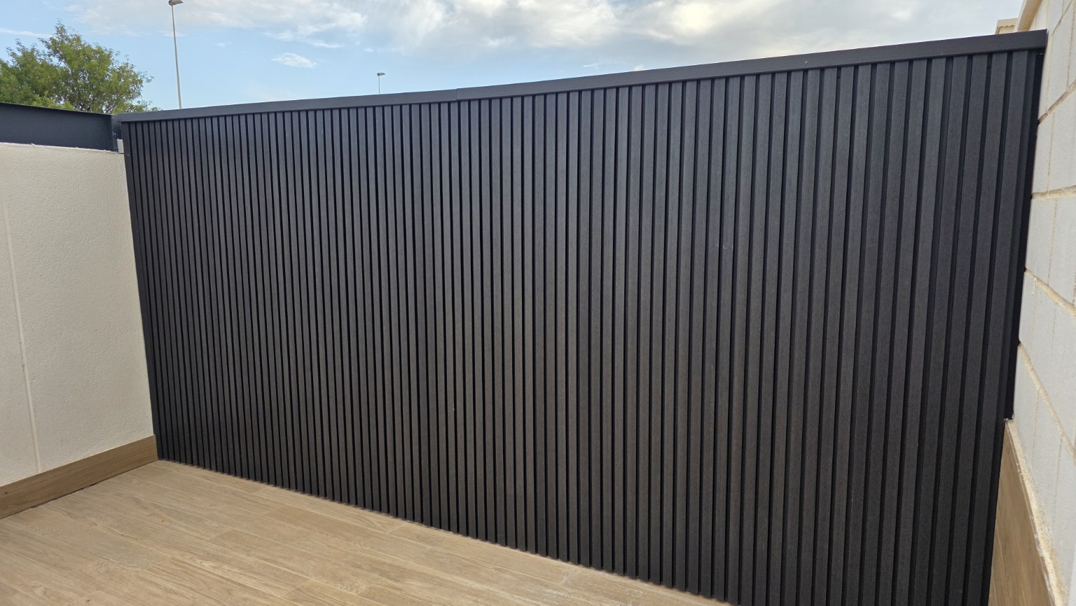 Pared exterior revestida con lamas de composite en una terraza