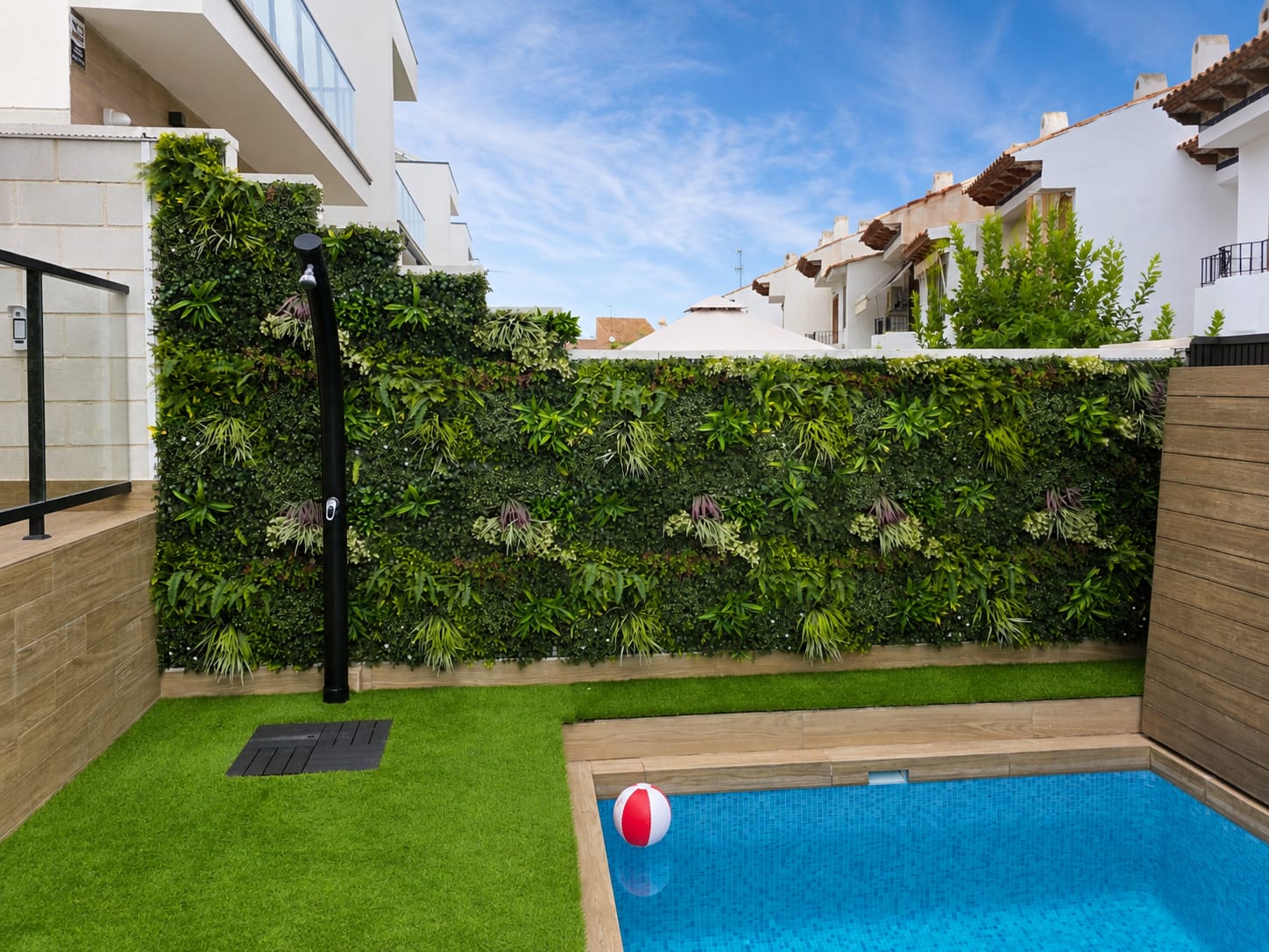Jardín vertical y césped artificial colocados en una terraza con piscina